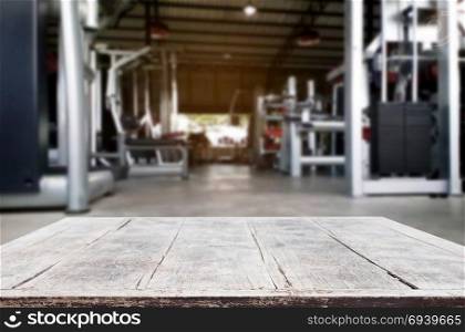 Wooden table on blurred background of fitness gym interior of modern club with equipment for your photomontage or product display