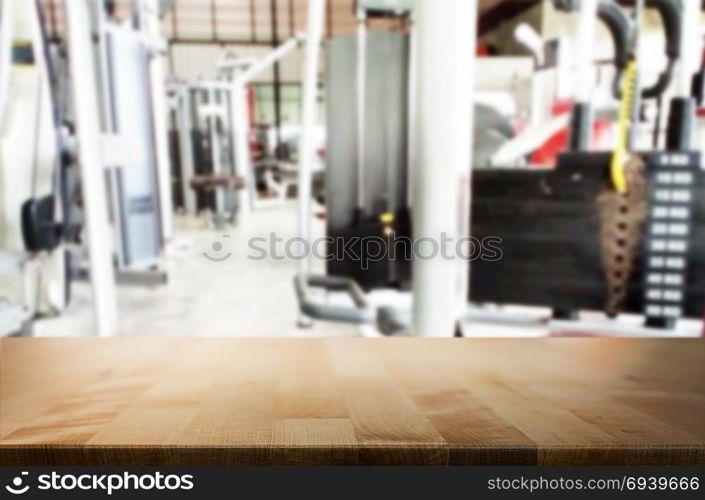 Wooden table on blurred background of fitness gym interior of modern club with equipment for your photomontage or product display