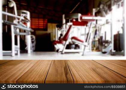 Wooden table on blurred background of fitness gym interior of modern club with equipment for your photomontage or product display