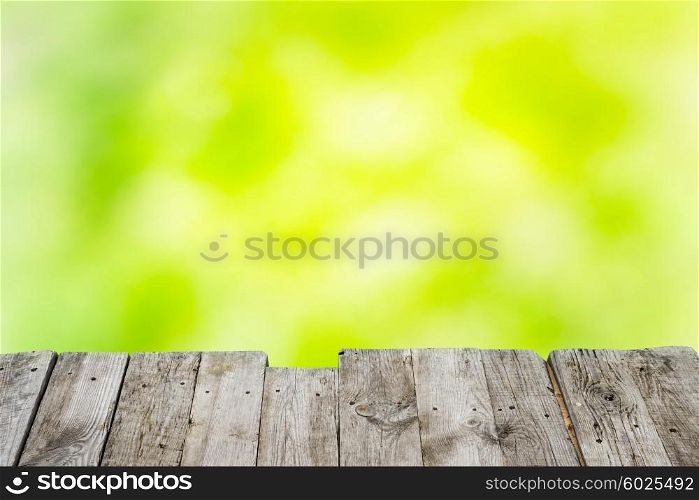 Wooden table over green and yellow spring light sunny background
