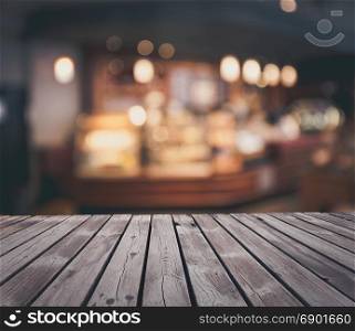 Wooden table top grunge surface over blur cafe interior background
