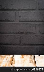 Wooden table top with black painted brick wall background