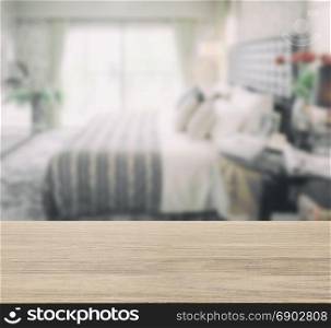 wooden table top with blur image of modern bedroom interior