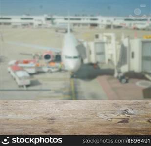 wooden table top with blur of aircraft and loading area at airport