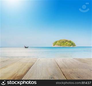 wooden table top with blur of beautiful seascape with blue sea beach island and the long tail boat under clear sky in summer,kata beach - phuket