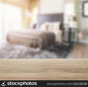 wooden table top with blur of bedroom in modern interior style