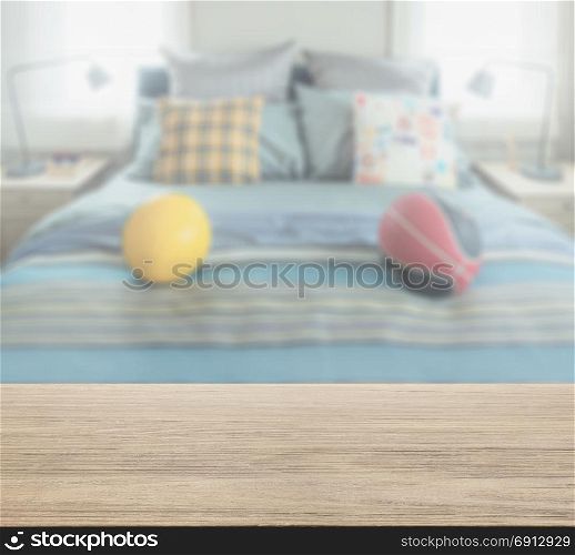 wooden table top with blur of bedroom with decorative pillow and football on bed