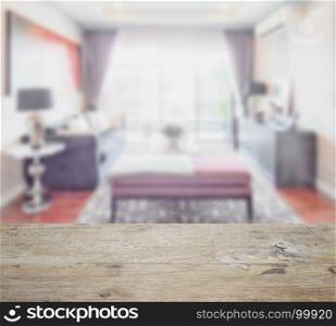 wooden table top with blur of classic style living room interior with sofa and bench