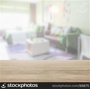 wooden table top with blur of colorful bedroom with brown sofa