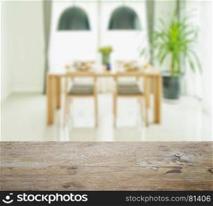 wooden table top with blur of dining table and chairs with elegant table setting