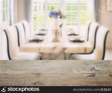 wooden table top with blur of dining table and comfortable chairs in vintage style effect