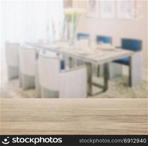 wooden table top with blur of dining table and comfortable chairs with elegant table setting