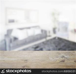 wooden table top with blur of modern bedroom with black sofa