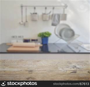 wooden table top with blur of modern ceramic kitchenware and utensils on the countertop