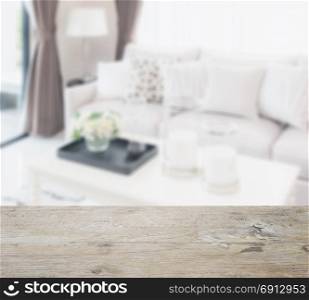 wooden table top with blur of modern living room design with sofa and lamp