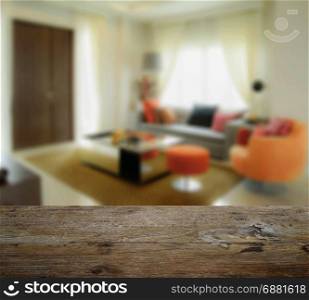 wooden table top with blur of modern living room interior with orange tone decoration