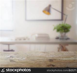 wooden table top with blur of modern working table with book and lamp as background