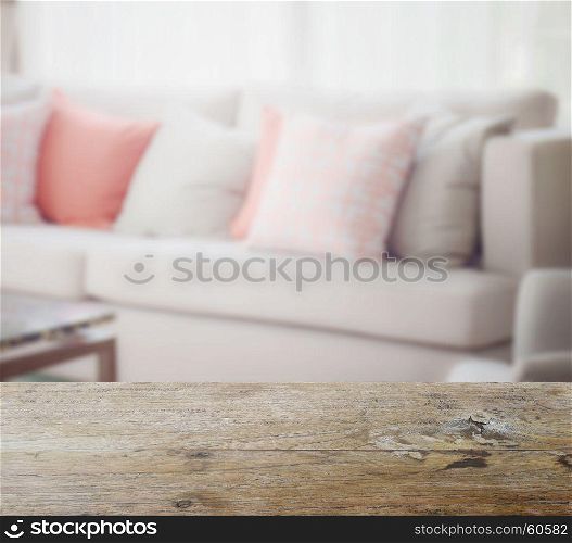 wooden table top with blur of orange and gray pillows setting on light gray in modern living room