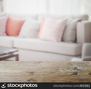 wooden table top with blur of orange and gray pillows setting on light gray in modern living room