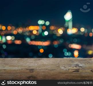 wooden table top with blurred abstract background of bangkok night lights downtown city view with bokeh