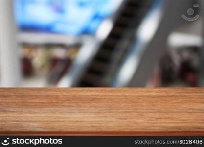 Wooden table top with blurred background of escalator in Airport
