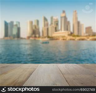 wooden table top with blurred skyline of singapore cityscape as background