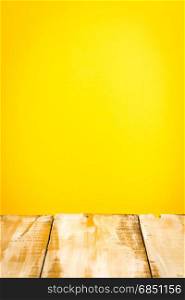 Wooden table top with yellow wall background