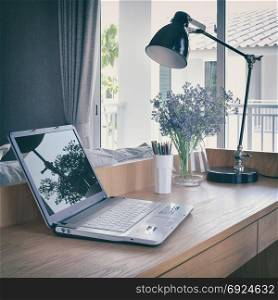 wooden table with computer notebook,pencil,lamp and artificial flowers in working area at home-vintage style filter