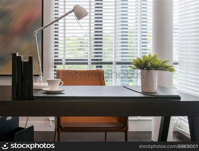wooden table with lamp and books in modern working room interior