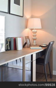 wooden table with lamp and books in modern working room interior