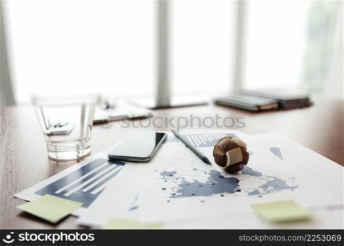 wooden texture globe with smart phone on business document in office desk as internet concept