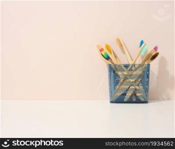 wooden toothbrushes in a plastic cup on a white table. Beige background, zero waste. Copy space