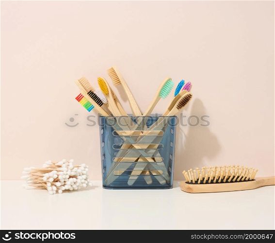 wooden toothbrushes in a plastic cup on a white table. Beige background, zero waste