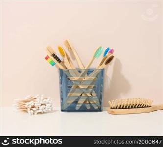 wooden toothbrushes in a plastic cup on a white table. Beige background, zero waste