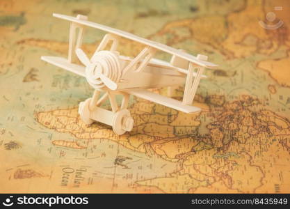 Wooden toy plane on world map on table. Travel and vacation concepts.