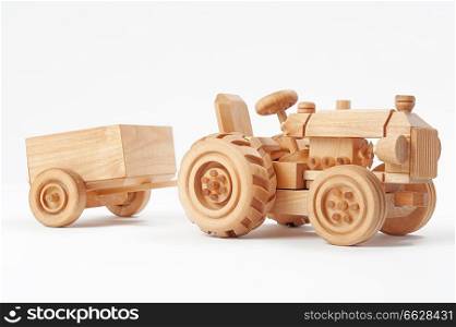 Wooden toy tractor with trailer on white isolated background