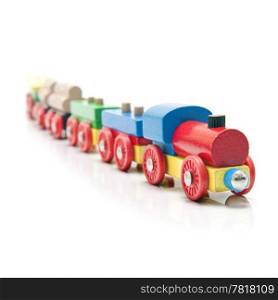 Wooden toy train with a locomotive and five carriages with a subtle reflection on a white background and a shallow depth of field