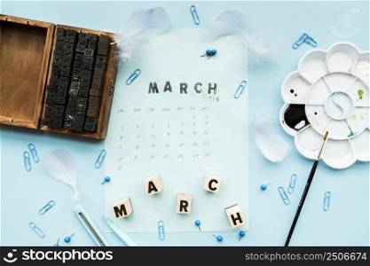 wooden typographic blocks feather march blocks march st&calendar with stationery against blue backdrop