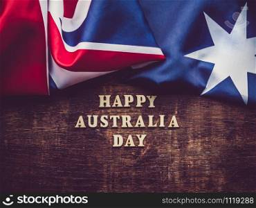 Wooden unpainted letters of the alphabet on a dark background. Australia Day. Beautiful, bright card. Top view, close-up. National holiday concept. Australia Day. Beautiful, bright card. Top view