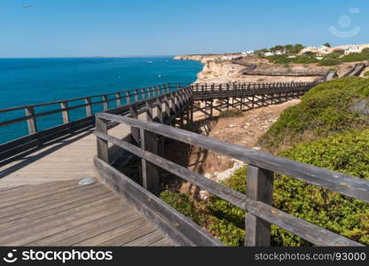 Wooden walkway to beautiful Carvoeiro beach with cliff and rock formation Algarve region Portugal.