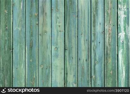 wooden wall of shed consisiting of blue green planks with faiding paint