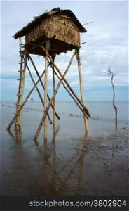 Wooden watch tower on Viet Nam beach at Mekong Delta, tower reflect on water, sea with black sand on day