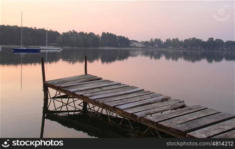 Wooden wharf on lake at sunrise