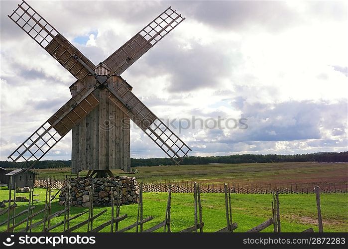 Wooden windmill against cloudy sky.