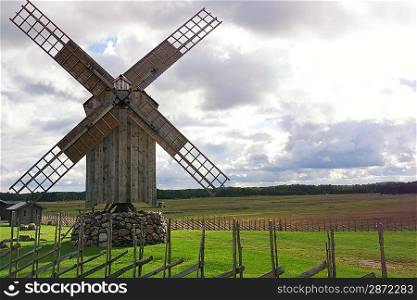 Wooden windmill against cloudy sky.