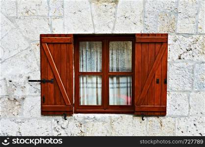 Wooden window with open shutters on the facade of a stone house in Spain. Retro style