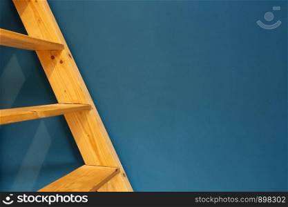 wooden yellow ladder on blue wall background. colorfull interior abstract space for text. wooden yellow ladder on blue wall background. colorfull interior abstract