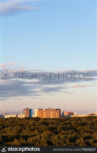 woods and apartment buildinds under blue sky in summer evening