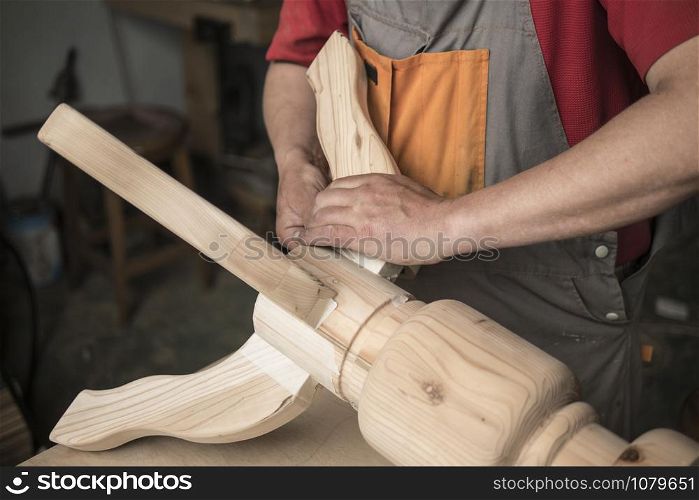 woodworker, carpenter makes a table with carved legs of pine. woodworking