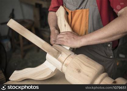 woodworker, carpenter makes a table with carved legs of pine. woodworking